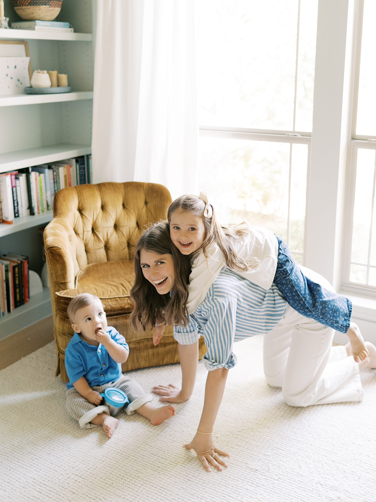 kids climb on mom playing on the floor of home