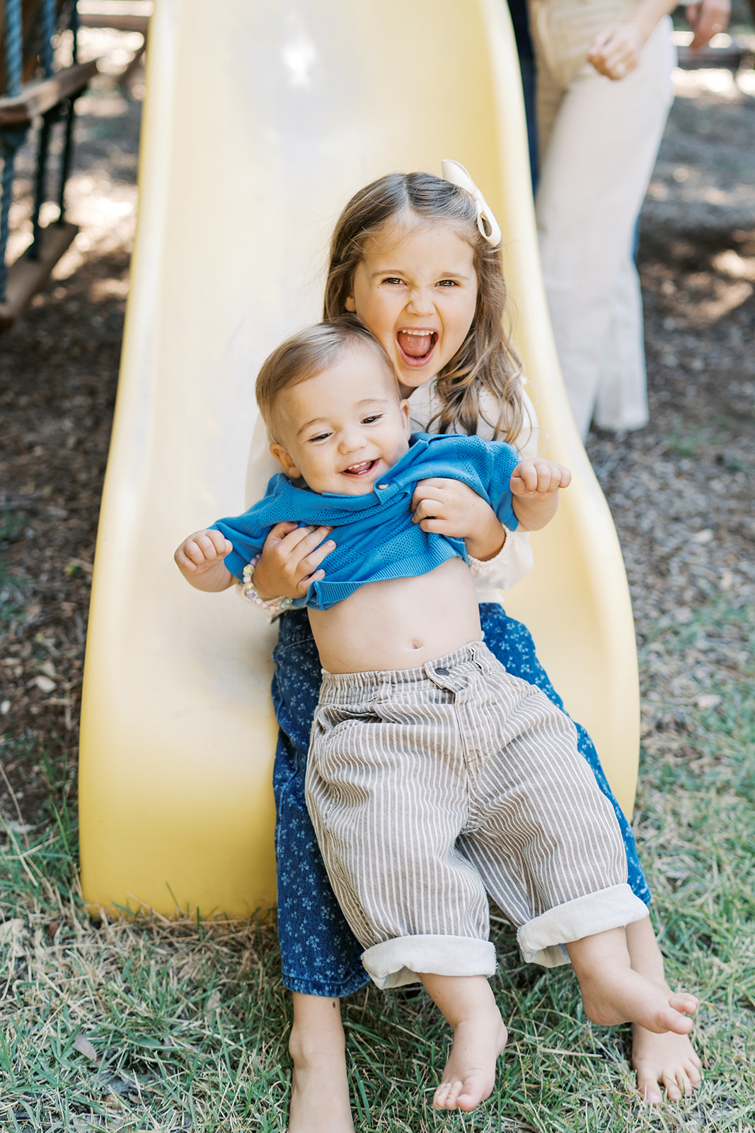 Candid photos of siblings going down slide together during family session | The Benefits of At-Home Family Sessions