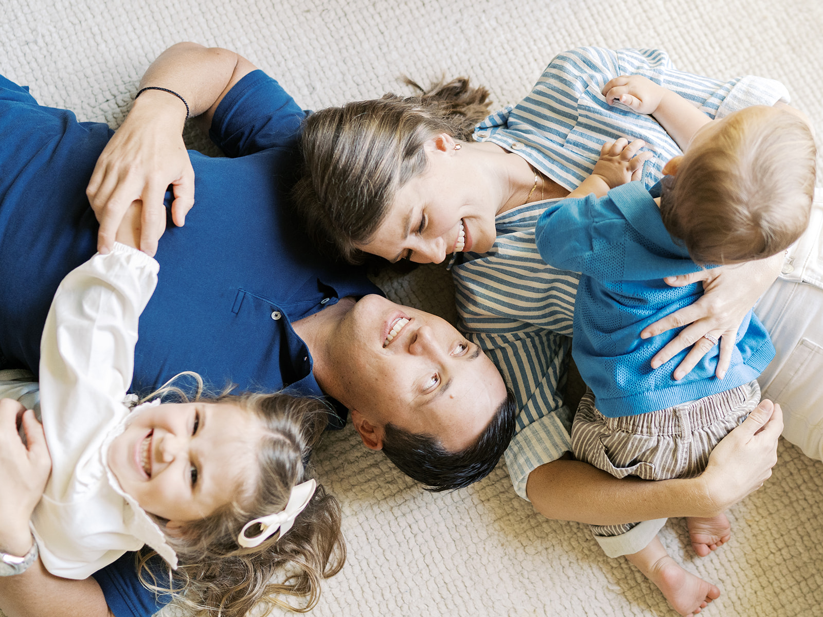 family of four lays on floor together |. The Benefits of At-Home Family Sessions