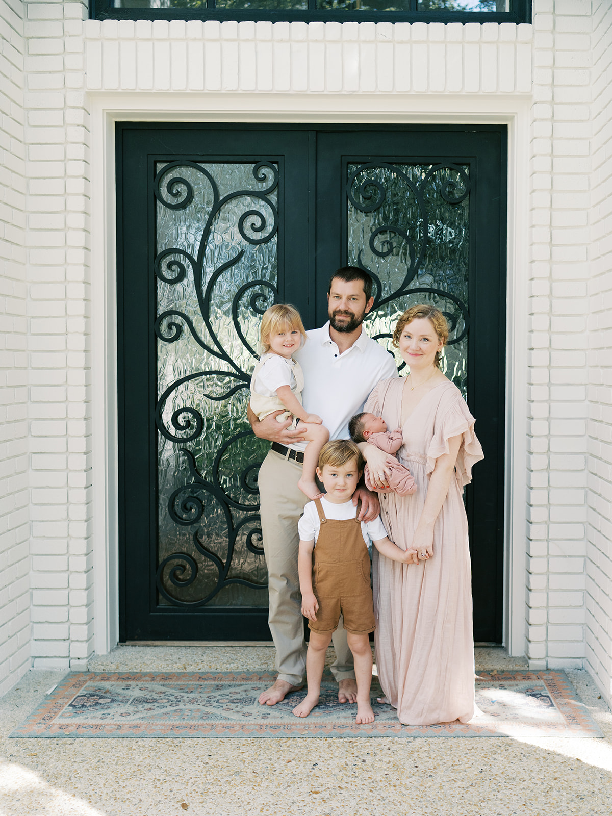 new family of five stands outside home