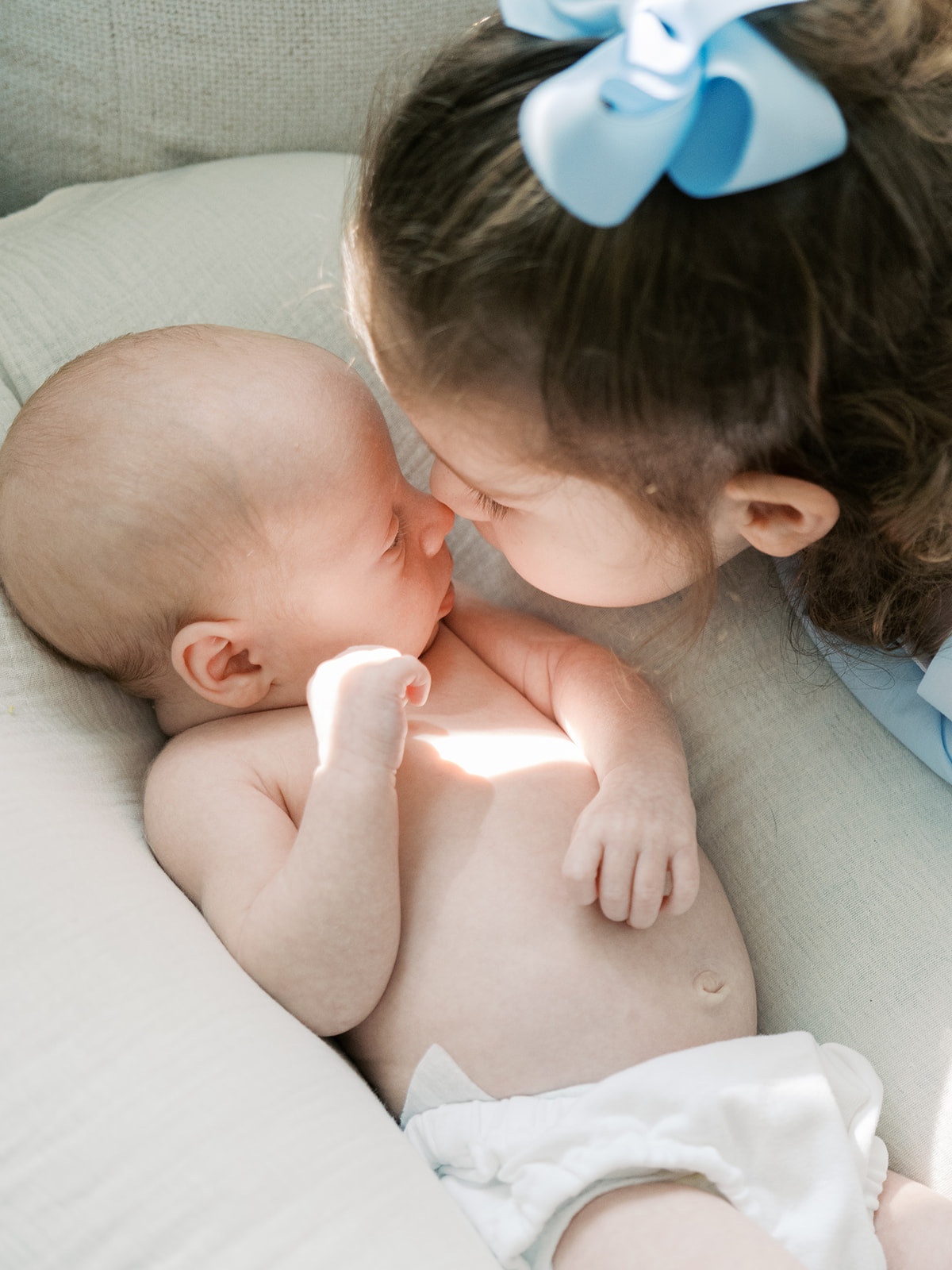 big sister nuzzles newborn sibling
