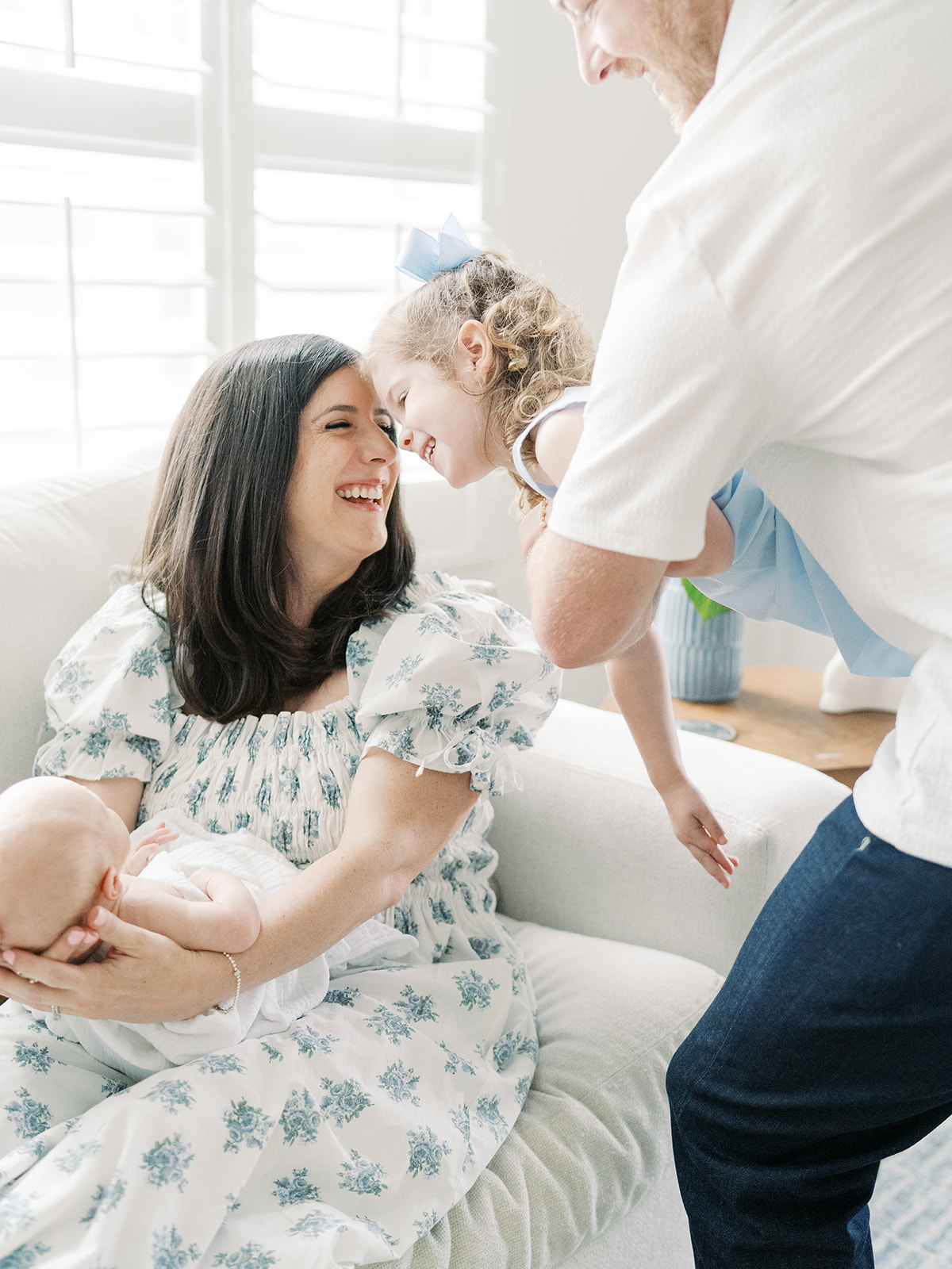 candid family photos of dad holding toddler girl up to mom holding newborn