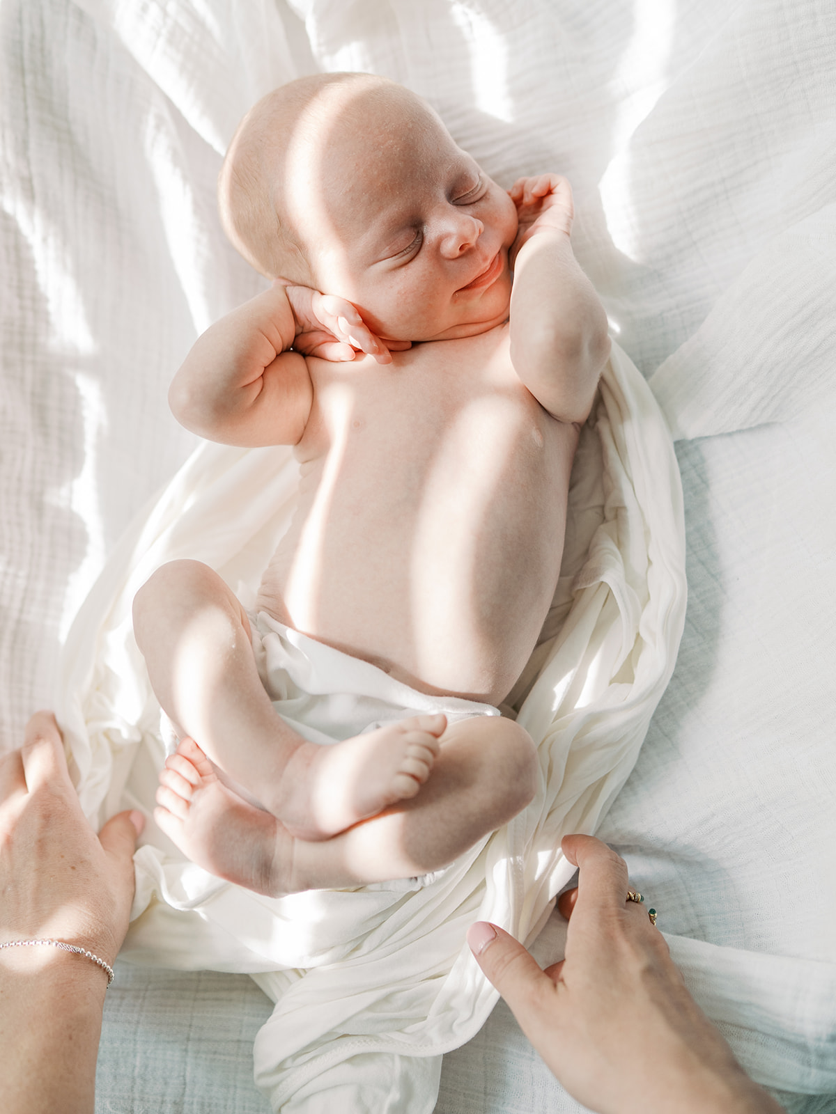 newborn sleeps surrounded by white blankets