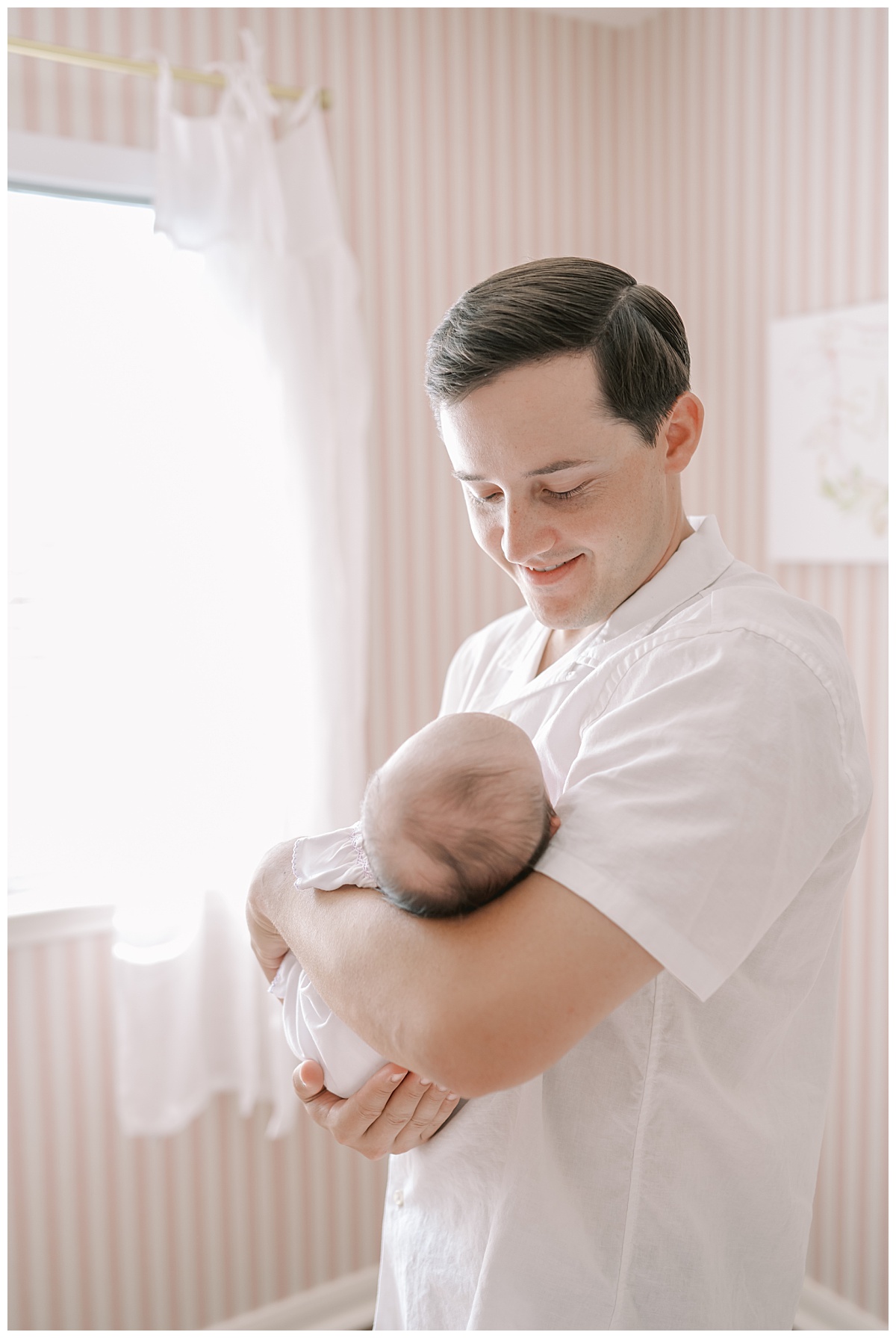 Dad holding baby girl in a pink nursery for their in-home newborn portraits in San Antonio, TX taken by Teressa Jane Photography, a San Antonio Newborn Photographer.