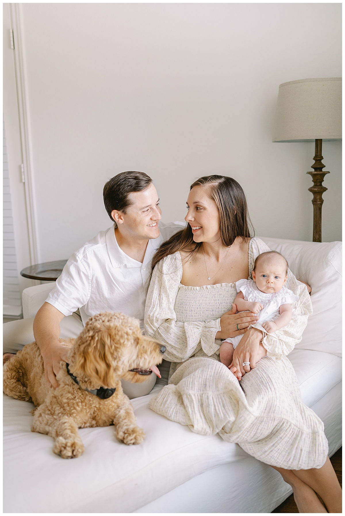 Mom and Dad snuggle with goldendoole and newborn baby girl for their in-home newborn session in San Antonio, TX taken by Teressa Jane Photography, a San Antonio Newborn Photographer.