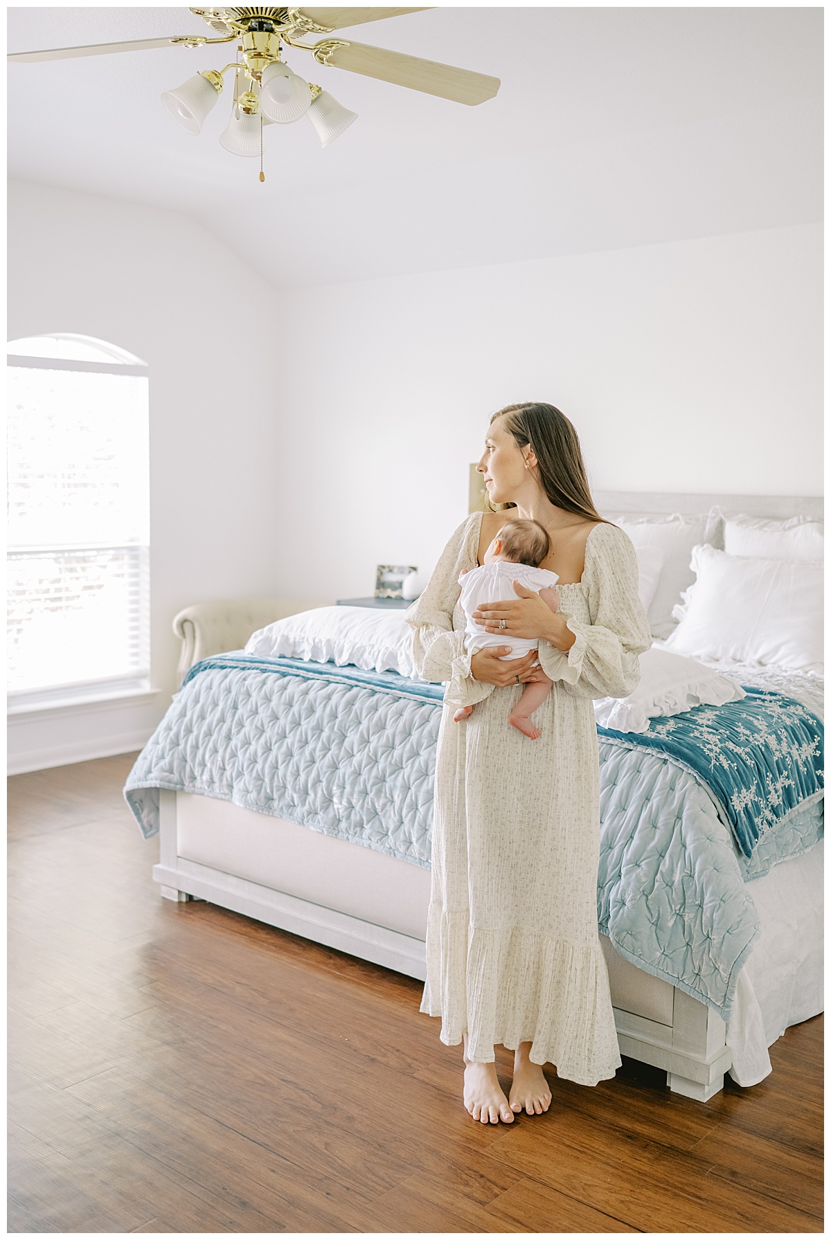 Mom holding baby girl in the master bedroom for their in-home newborn session in San Antonio, TX by Teressa Jane Photography.